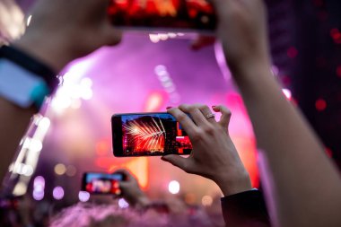 Akıllı telefonunu tutan ve konser fotoğrafı çeken bir adam.
