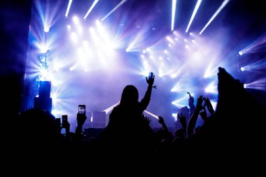 Kalabalık konserinin silueti, müzik hayranları. Kaldırılmış eller ve akıllı telefonlar.