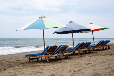 Kirli bir sahilde boş sandalyeler.