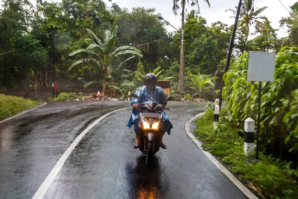Driving a scooter in the rain. Dangerous road in Asia