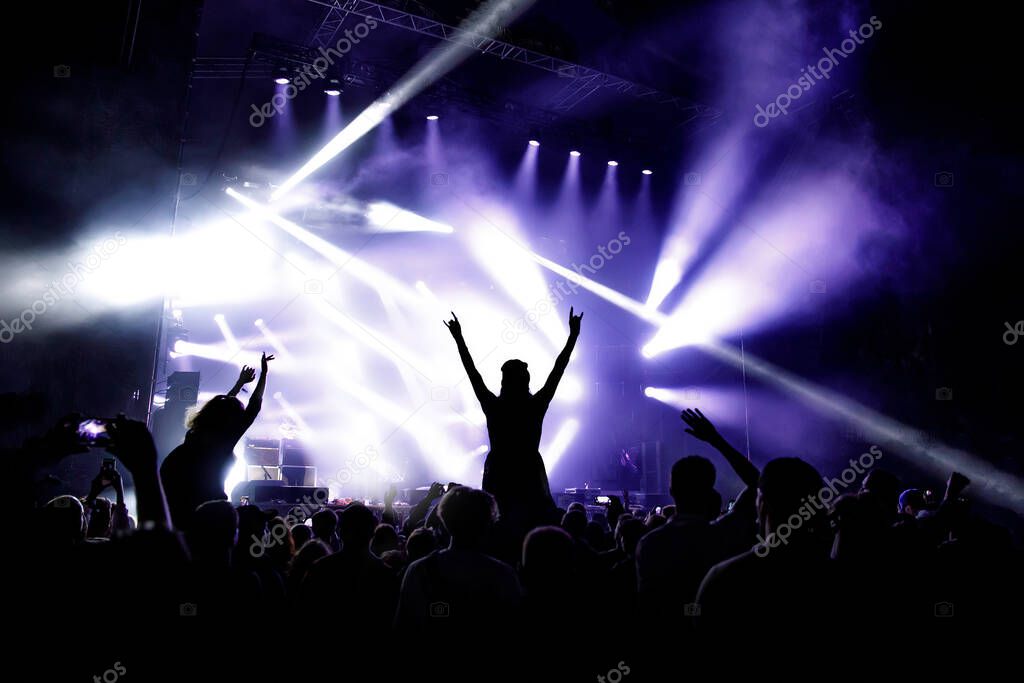 Silhouette of girl with raised hands enjoys the concert, music show