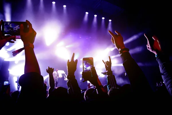 音楽祭でコンサートを見ながら楽しむ人たちの群衆 携帯電話で手を上げ — ストック写真