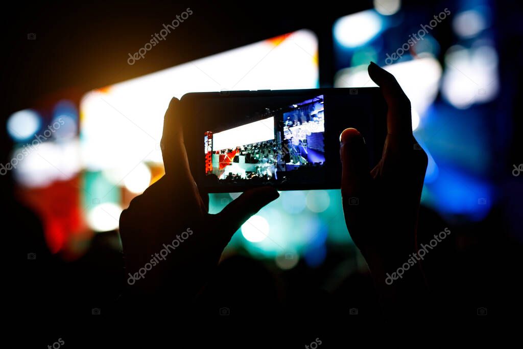 Smartphone silhouette in hands at a music show. Shooting of stage