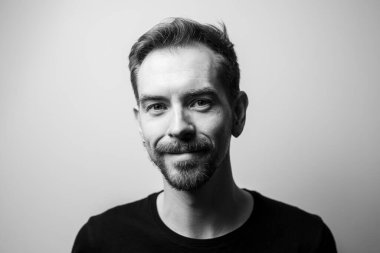 Gri arka planda gülümseyen genç adamın portresi. Siyah ve beyaz