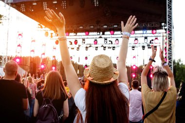 Açık hava müzik festivalinde elini kaldırmış bir kız.