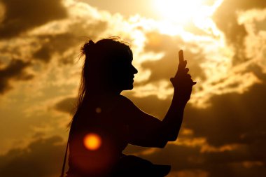 Yaz günbatımında bir kızın silueti. Müzik festivalini cep telefonuyla İnternet 'e aktar