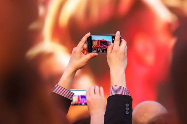 Sahne ışıklarının önündeki bir konserde cep telefonuyla fotoğraf çekmek.