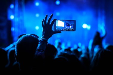 İnsanlar ellerinde akıllı telefonlar ve fotoğraf konseri tutuyorlar.