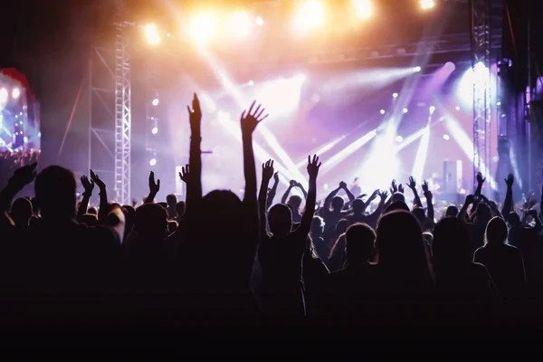 Rock concert, cheering crowd in front of bright colorful stage lights, Hands up with pleasure from the show