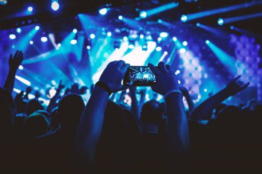 Adam konser salonunda akıllı telefon kullanarak gösterinin fotoğrafını çekiyor.