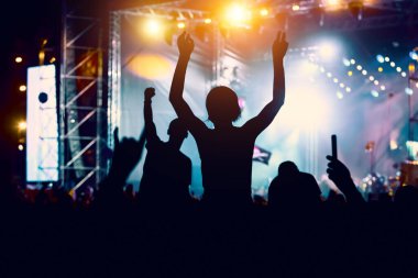 Halka açık bir etkinlikte insanlar. Eller havada siyah siluetler.