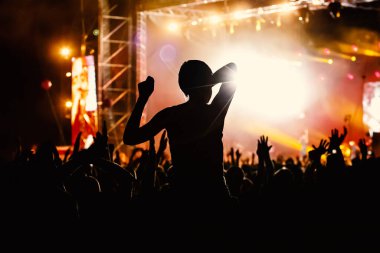 Halka açık bir etkinlikte insanlar. Eller havada siyah siluetler.