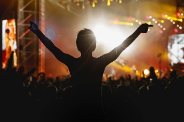 Müzik konserinde elini kaldırmış bir kız silueti..