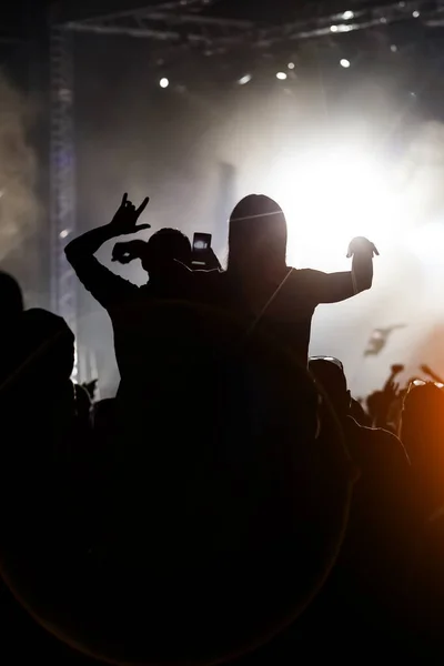 People at a public event. Black silhouettes with raised hands