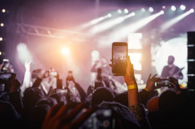 Umumi bir etkinlikte akıllı telefon kullanmak. Bir cep telefonunu elinizde tutmak ve fotoğraf ya da video içeriği çekmek.