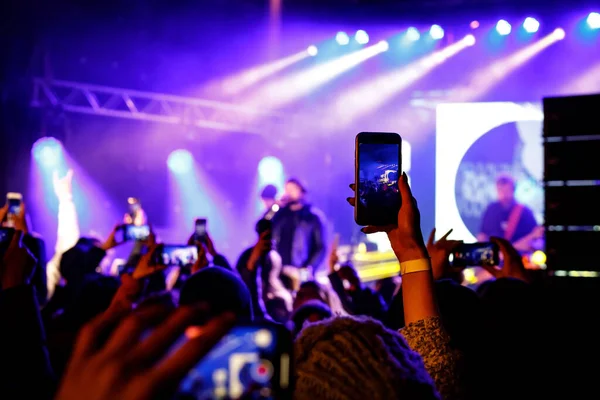 Recording a concert with mobile phone, silhouette of hands with smartphone