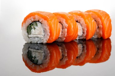 Cam bir masada dört Philadelphia suşi rulosu.