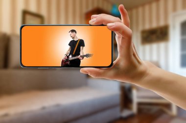 Evde akıllı telefondan şarkıcının çevrimiçi müzik performansını izliyorum. Canlı müzik videosu