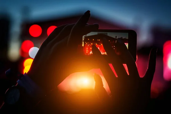 Silhouette of hand with a smartphone records live music festival, Taking photo of concert stage