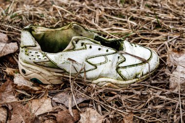 Kirli çimlerde eski yırtık ayakkabılar