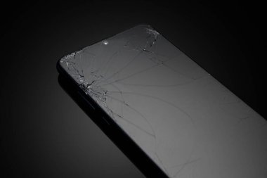 Siyah arka planda kırılmış cep telefonu ekranı.