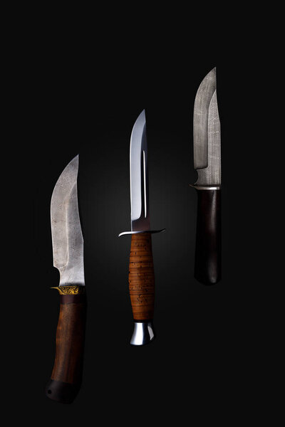 Set of knifes made of Damascus steel with a wooden handle on a isolated dark background.