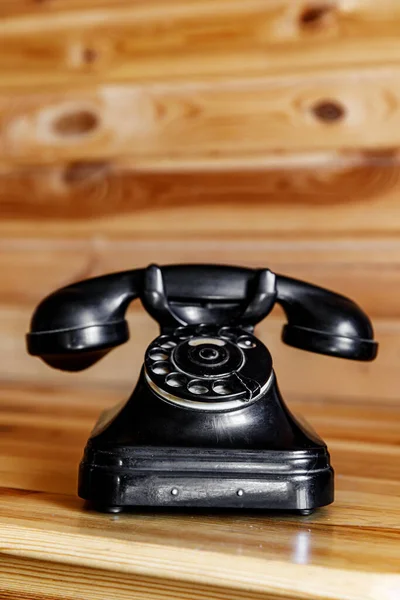 Old vintage black phone on wooden table