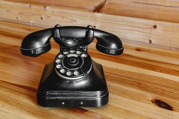 Old vintage black phone on wooden table