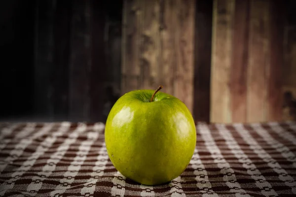Zielone jabłko na rustykalnym drewnianym tle. — Zdjęcie stockowe