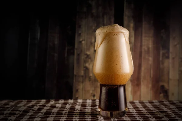 Un bicchiere di birra scura su sfondo di legno. Stout nel bar. — Foto Stock