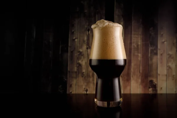 Um copo de cerveja escura sobre fundo de madeira. Stout em bar. — Fotografia de Stock