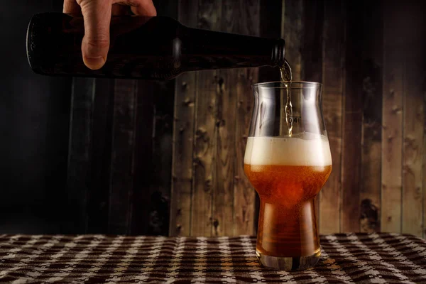 Despejando cerveja no copo da garrafa em fundo de madeira. — Fotografia de Stock