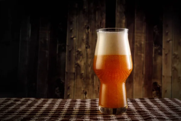 Un vaso de cerveza con espuma grande sobre fondo de madera. — Foto de Stock