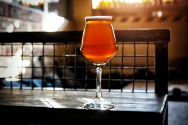 Bira barında, ahşap masanın üzerinde ince bir bira sapının üzerindeki cam.