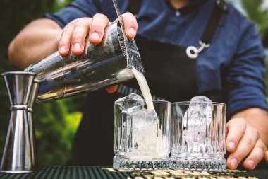 Barmen bardağa buzlu bir kokteyl dolduruyor..