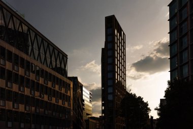 Günbatımında sıcak tonlar ve cam yansımalarla Londra şehrinin çağdaş mimarisi.