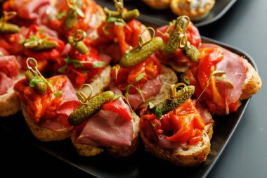 İştah açıcı et kanepeleri turşu ve kırmızı biberle servis edilir. Yemek ve resepsiyonlar için şenlikli ve lezzetli bir parmak yemeği..