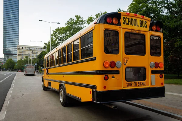 Klasik bir sarı okul otobüsü açık bir günde banliyöde yol alır..
