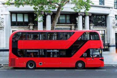 Kırmızı bir çift katlı otobüsün yan görüntüsü Londra caddesinde durdu. Tarihi taş mimarisinin önünde..