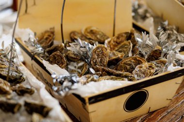 Buzdaki taze istiridyelerle dolu, yapraklarla süslenmiş ve sunum için gümüş kağıtlarla süslenmiş tahta kutular..