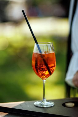 Güneşli bir günde açık havada servis edilen açık turuncu Aperol sprey kokteyli ve buz küpleri..
