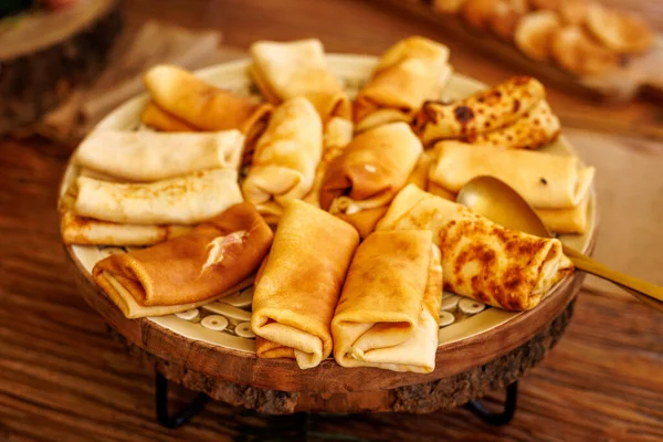 Yuvarlak, ahşap servis tepsisine yerleştirilmiş, yemeye hazır altın katlanmış gözlemeler..