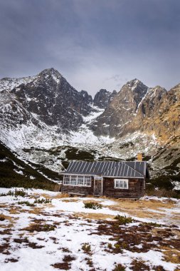 Karlı vadideki ahşap dağ kulübesi sarp kayalık tepeler ve dağlık arazilerle çevrili..