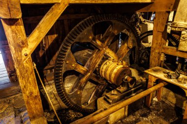 Geleneksel bir yapıda muhafaza edilmiş eski ahşap değirmen dişlileri ve mekanizmalarının detaylı bir görüntüsü.