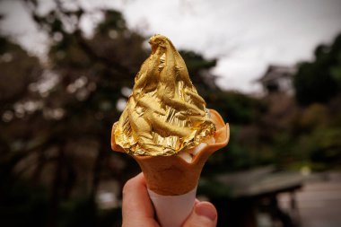 Dekoratif altın yaprağıyla kaplı yumuşak bir dondurma külahının yakın çekimi. Arka plan bulanık. Detaylı altın dokusuna odaklanıyorum..