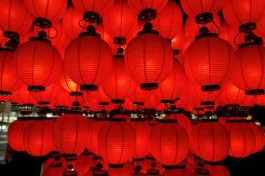 Parlayan kırmızı fenerlerin yoğun bir dizilişi başınızın üzerinde asılı, sıcak ve atmosferik bir aydınlatma deseni oluşturur.