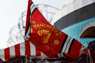 Manchester, İngiltere - 17.08.2025: Eski Trafford Stadyumu yakınlarında kulüp arması rüzgarda dalgalanan Red Manchester United bayrağı.