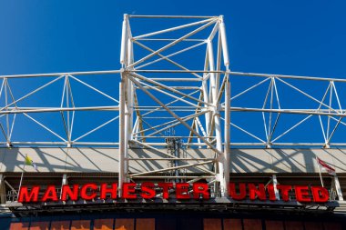 Manchester, İngiltere - 17.08.2025: Manchester United harfleri açık mavi gökyüzüne karşı beyaz metal kirişlerle stadyumun çatısında duruyor.