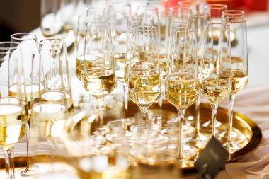 Parlak altın bir tepside köpüklü şarap standıyla dolu çoklu şampanya kadehleri. Düzenleme şenlik ortamını yansıtıyor.