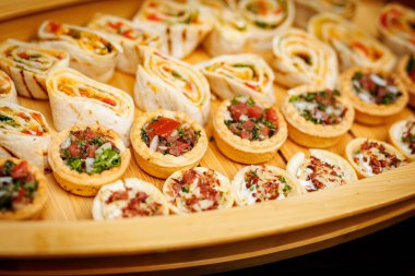 Bir tepsi çeşitli sarmalar ve sebze ve otlarla dolu küçük tartlar..